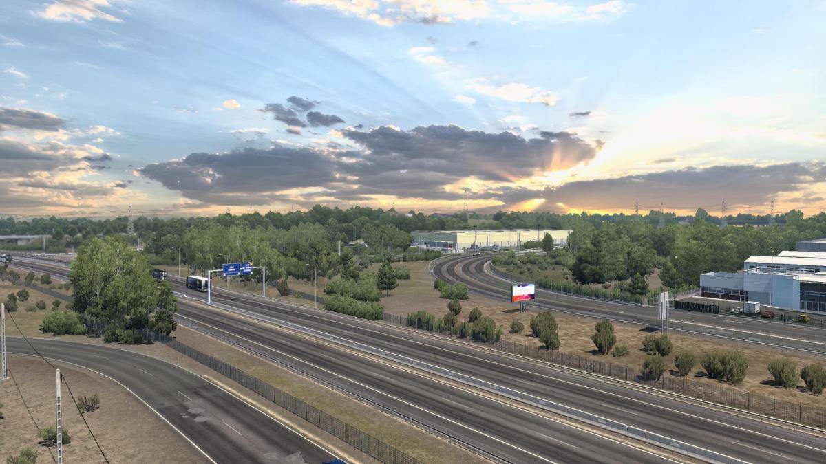 A highway scene with sun breaking through clouds.